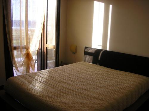 a bedroom with a bed and a window with a curtain at Baglio Makari in San Vito lo Capo