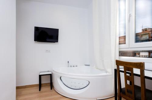 Habitación con TV y bañera blanca. en GOLDEN TORREJON, en Torrejón de Ardoz