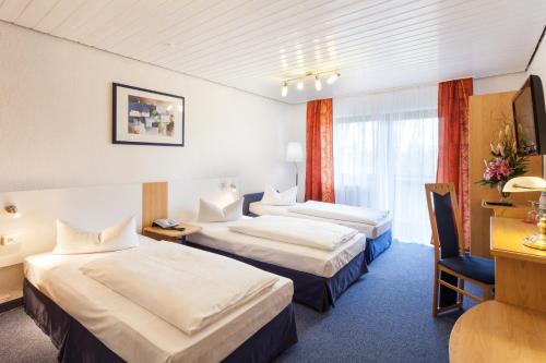 a hotel room with two beds and a desk at Akzent Hotel Alpenrose in Nesselwang