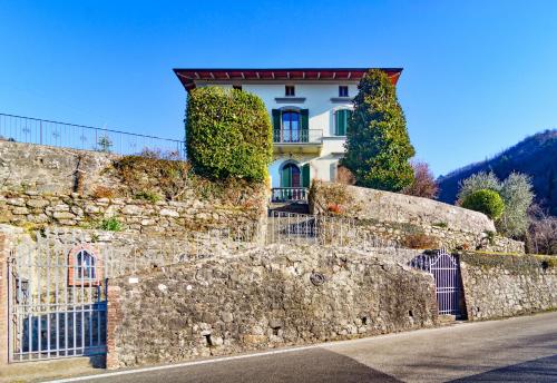 a house behind a stone wall with a fence at La Limonaia di Casagrande in Barga