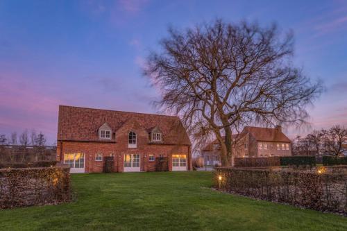 a large brick house with a tree in the yard at HuysHoeve in Knokke-Heist