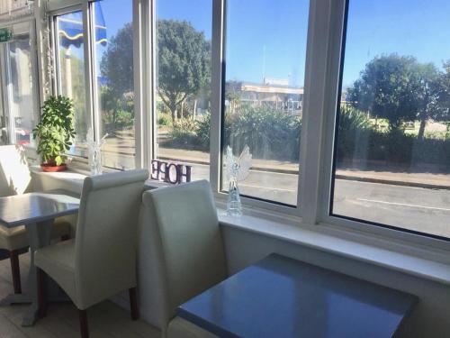 a dining room with a table and chairs and windows at Seaview Sanctuary in Eastbourne