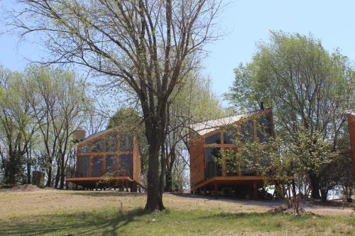 una casa de madera con un árbol en un campo en Ayres del Champaqui en Villa General Belgrano