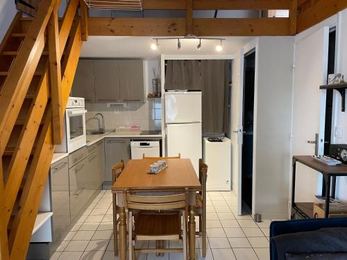 une cuisine avec une table et un réfrigérateur blanc dans l'établissement Vacances en famille !, à Saint-Hilaire-de-Riez