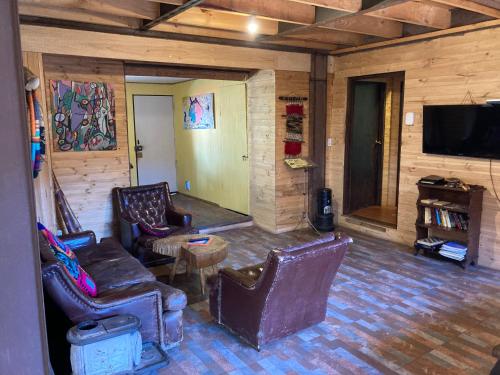 a living room with leather chairs and a flat screen tv at Willhouse Hostel in Pucón