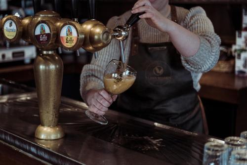 a bartender is pouring a drink into a glass at 's Lands Welvaren in Aardenburg