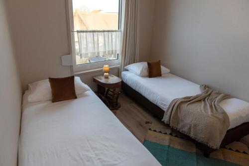 two beds in a small room with a window at 's Lands Welvaren in Aardenburg