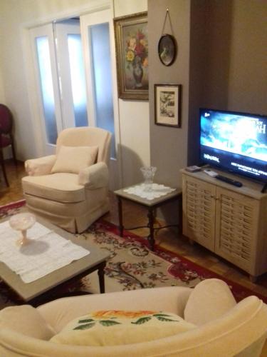 George appartment في أثينا: غرفة معيشة مع تلفزيون وأريكة وكراسي