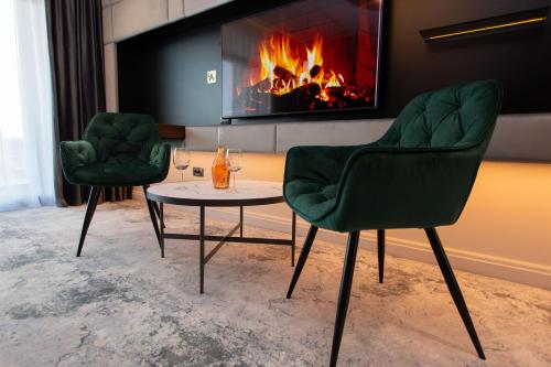 two green chairs and a table in front of a fireplace at Vila Avy in Haţeg