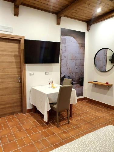 a dining room with a table and a television on the wall at Setteabbracci Suite & Apartments in Baronissi