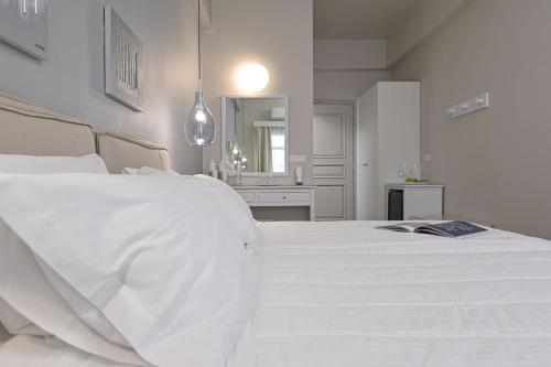 a white bed in a white bedroom with a bathroom at Hotel Grotta in Naxos Chora