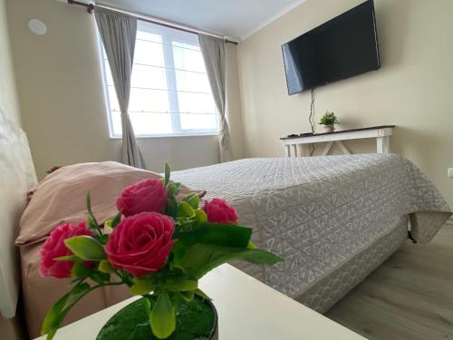 a bedroom with a bed and a vase of roses on a table at Refugio Los Volcanes. in Osorno