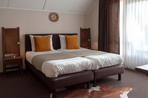 a bedroom with a large bed with orange pillows at 's Lands Welvaren in Aardenburg