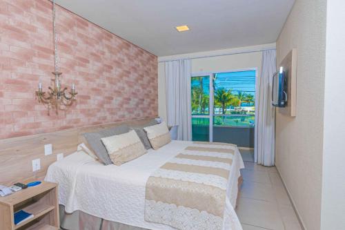 a bedroom with a bed and a view of the ocean at Hotel VillaReal Charme in Guaratuba