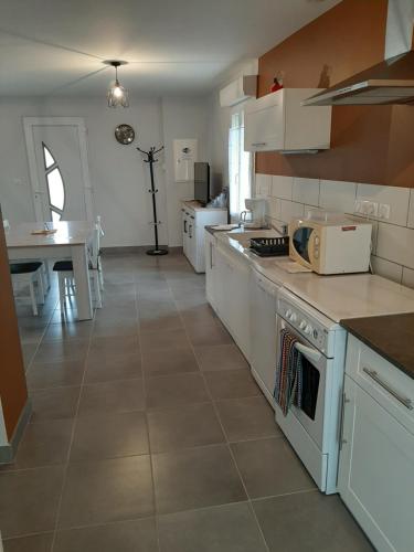 uma grande cozinha com electrodomésticos brancos e uma mesa em Gîte Les Grands Prés em Frontenard