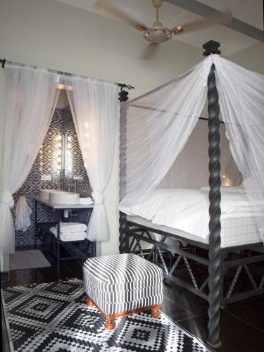 a bedroom with a canopy bed and a table at RoofTop Boutique Hotel Adults Only in Serekunda