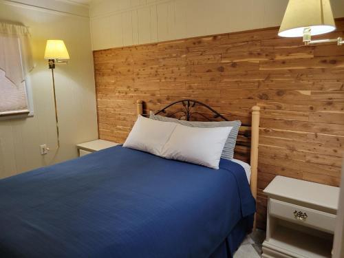 1 dormitorio con cama azul y pared de madera en Husker Inn, en North Platte