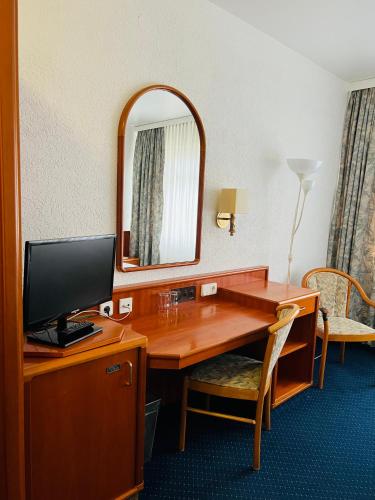 a room with a desk with a television and a mirror at Hotel Weller Kahl am Main in Kahl am Main