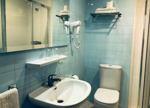 W wyłożonej niebieskimi kafelkami łazience znajduje się umywalka i toaleta. w obiekcie Hotel Sur w mieście Cala Bona