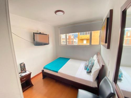 a small bedroom with a bed and a tv at Hotel Arena Plaza Inn in Bogotá