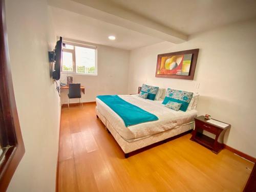 een slaapkamer met een bed met blauwe lakens en een raam bij Hotel Arena Plaza Inn in Bogota