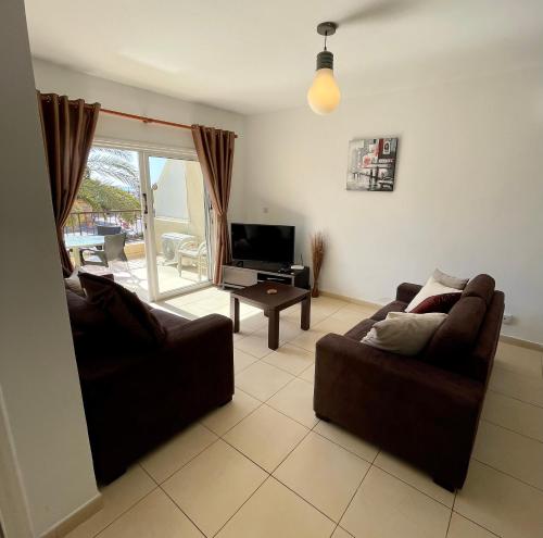 a living room with two couches and a television at 109 Queens Gardens, Paphos in Paphos City