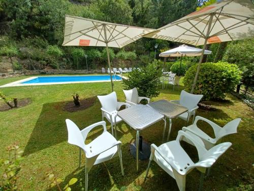 eine Gruppe weißer Stühle und Tische mit Sonnenschirmen in der Unterkunft Casa Fuente de Rechita in La Iruela