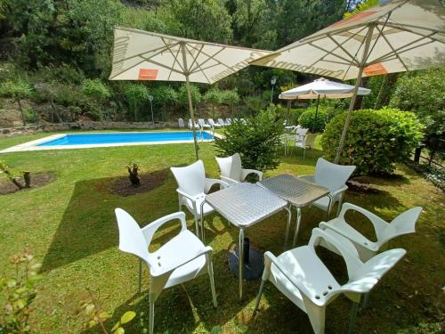 a group of white chairs and tables with umbrellas at Casa Fuente de Rechita in La Iruela