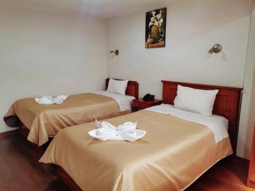 a room with two beds with white flowers on them at Hotel Urpi Cusco in Cusco