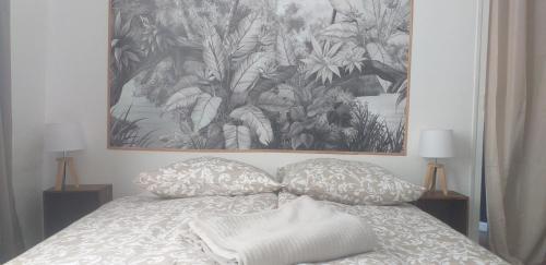 a bed with two pillows and a painting on the wall at Maison cosy à Ury in Ury