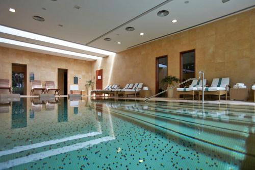 a swimming pool in a hotel with white chairs at Villa Bougainvillea Palheiro Village by Holiday Rental Madeira in Funchal