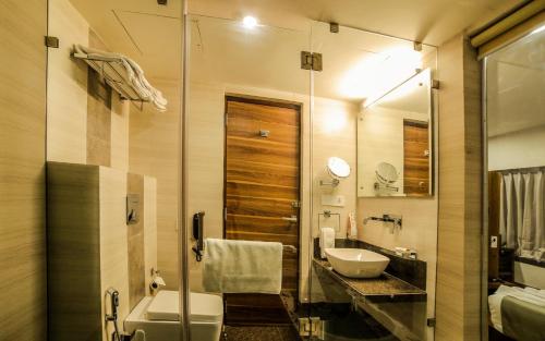 a bathroom with a sink and a toilet and a mirror at The Basil Park in Bhavnagar