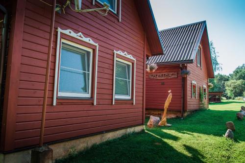a red house with a yard next to it at Taparynė in Alanta