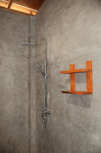 a shower with a wooden shelf on the wall at Eco Village in Ella