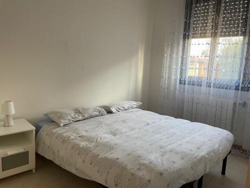a white bedroom with a bed and a window at la casa di Ste' in Milan