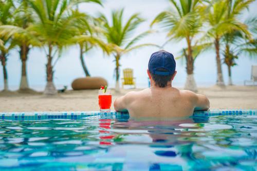 a man sitting in a swimming pool with a drink at Quinta del Mar La Joya in Tolú