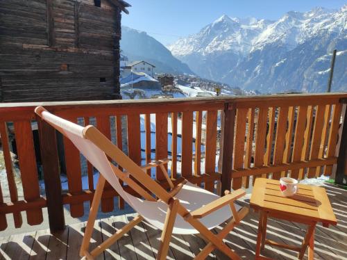 a chair sitting on a deck with a cup of coffee at Apartment mit Traumblick im Haus Olympia in Grächen