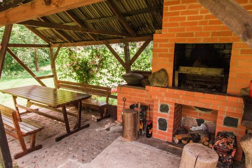 a patio with a brick fireplace and a picnic table at Taparynė in Alanta