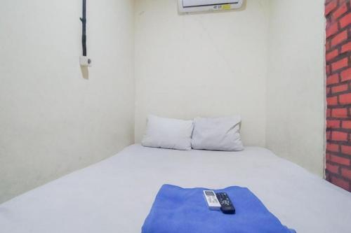 ジャカルタにあるSwahouse Tanjung Priok Syariah Mitra RedDoorzの白いベッド(リモコン付)