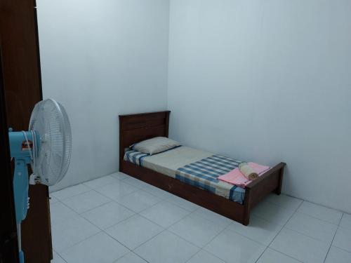 a small bed in a room with a fan at Pelangi homestay in Kampung Bota Kiri