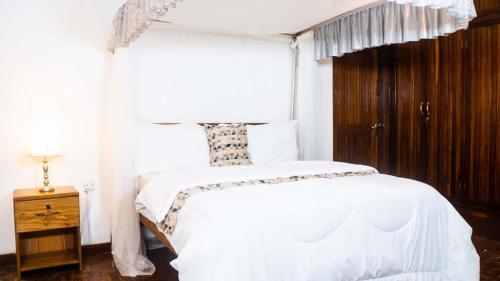 a bedroom with a white bed and a window at Upper Hill Place in Dar es Salaam