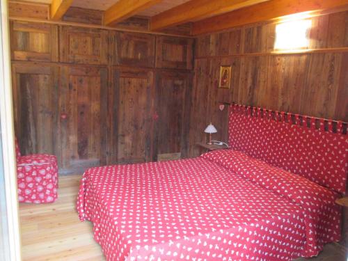 a red bed in a room with wooden walls at Chalet Borney in Fontainamore