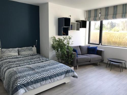 ein Schlafzimmer mit einem Bett, einem Sofa und einem Fenster in der Unterkunft Au Calme in Sint-Genesius-Rode