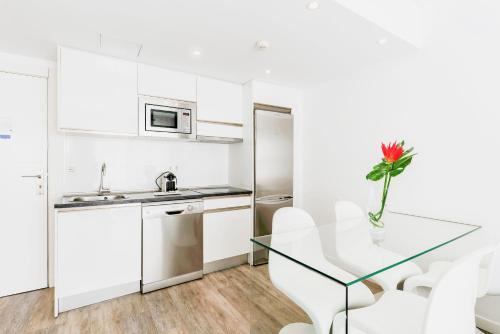 een witte keuken met een glazen tafel en witte stoelen bij Bristol Sunset Beach - Holiday Apartments in Corralejo