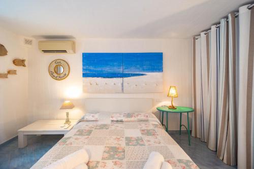 a white bedroom with a bed and a green table at BGItalianVacation - Ville Li Conchi in Castiadas
