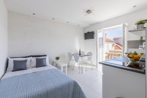 a white bedroom with a bed and a table with chairs at Apartment Anna - 20 m from the sea in Postira