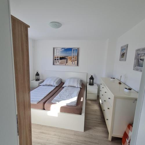 a white bedroom with a bed and a desk at Wohnung "Orther Hafen" in Bannesdorf auf Fehmarn in Fehmarn