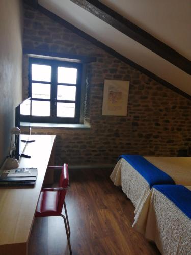 a bedroom with a bed and a desk and a window at Posada Real de Las Misas in Puebla de Sanabria