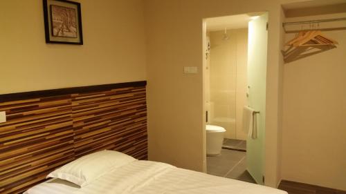 een slaapkamer met een bed en een badkamer met een toilet bij Hotel Sri Iskandar in Kota Kinabalu