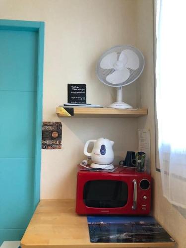 un four micro-ondes rouge assis au-dessus d'une table dans l'établissement LOGEMENT SYMPA ENTRÉE INDÉPENDANTE PRÈS BORDEAUX 10kms, à Tresses